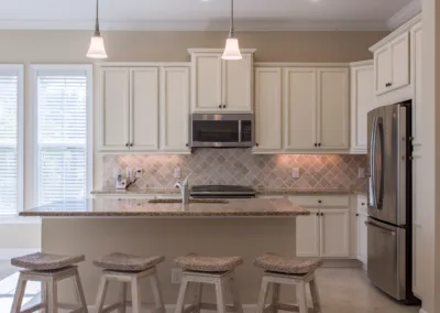 A kitchen with white cabinets and stools.